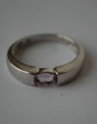A hallmarked 9ct white gold ring set with a single oval cut pale purple stone.  Hallmarked