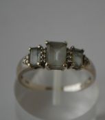 A hallmarked 9ct white gold ring set with three pale blue emerald cut stones with diamond accents.