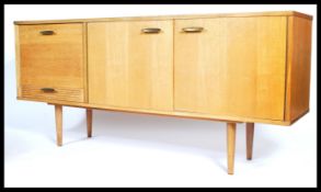A 1970's retro light teak wood sideboard of low and long form being raised on tapering legs having a