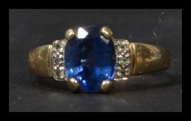 A hallmarked 9ct gold sapphire and diamond ring having a central oval cut blue sapphire flanked by
