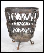 A 20th century cast and wrought iron strapwork log basket being raised on c-scroll feet having