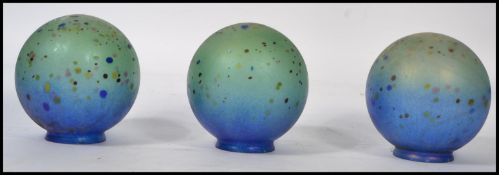 A set of 3 20th century globular loetz style irridescent glass lamp shades. Each with raised foot