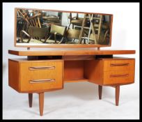 A 1970's retro teak wood G-Plan Kelso dressing table having pedestals of drawers raised over tapered