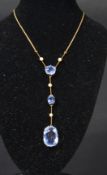 An early 20th century 18ct gold violet blue sapphire and seed pearl necklace having three faceted
