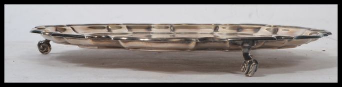 A silver hallmarked large salver tray raised on scrolled leg having a scalloped pie crust edge.