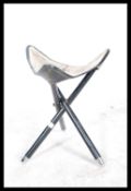 A 1970's Safari stool being raised on an ebonised folding tripod vase having a good pony skin hide