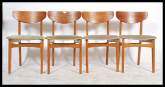 A set of four 20th century retro teak wood dining chairs being raised on turned and tapering