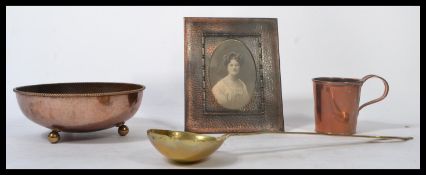 An arts and crafts copper Dryad Lester hammered bowl resting on three brass ball feet along with a