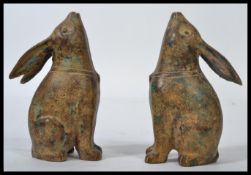 A pair of cast bronze figurines modelled as rabbits looking skywards whilst sat on their hind