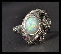 A sterling silver ring in the form of a snake with opal panel heat and inset ruby eyes. Weighs 7