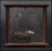 A Chinese silver model of a Junk boat raised on a carved base in the form of waves held within a