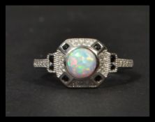 A sterling silver art deco style ring having central opal with sapphires and cz stones. Weighs 3.5