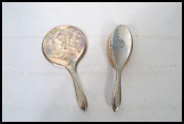 A silver hallmarked matching brush and mirror with monograms. The mirror having a bevelled glass