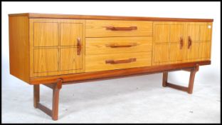 A mid century Avalon teak wood sideboard raised on shaped legs with a wide and low body comprising a