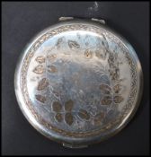 A silver hallmarked ladies compact, cast in relief with foliate design to the lid, machine turned