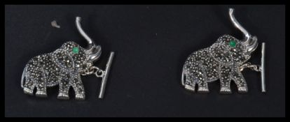 A pair of sterling silver earrings in the form of elephants with emerald set eyes and marcasite
