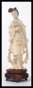 A Japanese ivory Okimono of a bijin, Meiji period, the young woman carved standing holding a