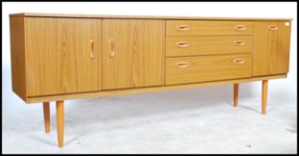 A retro mid century faux teak wood sideboard of low and wide proportions being raised on shaped legs