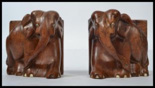 A pair of early 20th century hard wood bookends modelled as African elephants with ivory toes and