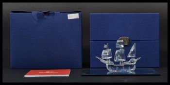 A boxed Swarovski crystal glass model of a ship entitled Santa Maria on glass mirror base. In box.