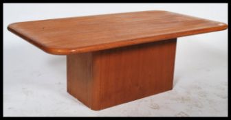 A20th century large retro teak wood coffee table having a rectangular thick top raised on squared