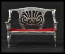 A sterling silver antique style miniature model of a lyre back sofa with red baize cushion. Weighs
