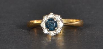 An 18ct gold diamond and sapphire ring having a central sapphire stone with a halo of diamonds. Size