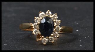 A 9ct gold sapphire and diamond ring. Central stone approx 7mm long with a halo of diamonds ( one