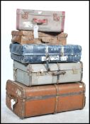 A stack of 5 vintage 20th century suitcases to include a canvas bound wooden steamer trunk, mid