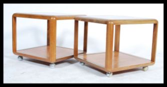A pair of 20th century 1970's retro G-Plan teak wood and glass square coffee tables being raised