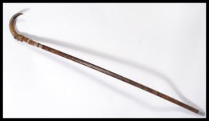 A vintage 20th century walking stick cane having a tapering wooden shaft with white metal silver