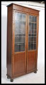 A vintage 20th century circa 1920's oak glazed tall library bookcase cabinet. The cupboard two
