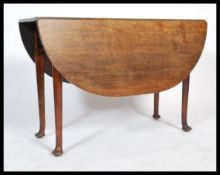 A 19th century Georgian country oak drop leaf dining table being raised on turned, tapering legs