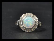 A sterling silver art deco ring set with a central opal and a halo of CZ stones. Within jewellery