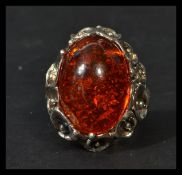 A sterling silver and substantial amber cabochon ring with pierced floral mount. In box. Weighs 17.2