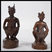 A pair of early 20th century wooden Balinese figures carved as people holding chickens. Please see
