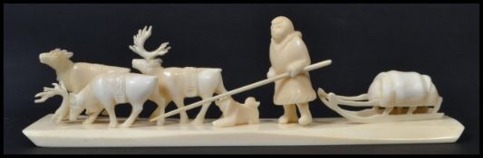 An early 20th century North American bone carving of an Inuit scene depicting elk pulling a sleigh