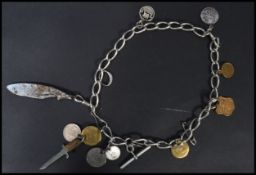 A silver hallmarked pocket watch fob chain with several attached charms to include coins, a