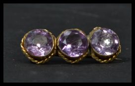 A late 19th century Victorian yellow metal three stone amethyst brooch.