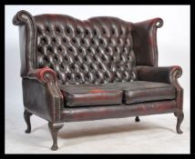 A 20th century Antique style oxblood leather chesterfield two seat sofa settee being raised on
