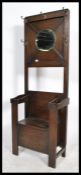 An early 20th century oak hall stand settle bench of upright form with mirror back having  four
