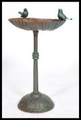 A 20th century cast iron pedestal bird bath. The scalloped shaped bath surmounted with two birds