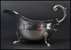 A silver hallmarked creamer raised on hoof feet with scalloped edges and c-scroll handle. Hallmarked
