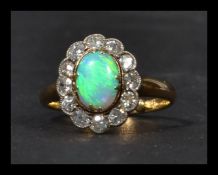 An 18ct gold opal and diamond ring having a fantastic central opal with a halo of old cut diamonds