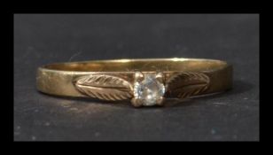A vintage 9ct gold solitaire ring set with a single white stone with stylised leaf shoulders. Marked