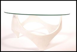 A mid century atomic era glass topped coffee table having a white painted wooden body having a space