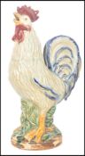 An early 20th century ceramic figurine of a cockerel having brightly coloured glazed finish,