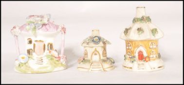 A group of 3 19th century pastille burners in the shape of cottages one being encrusted in flower,