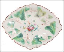 An 18th century Chelsea Derby lozenge shaped dish decorated with leaves and floral spray to