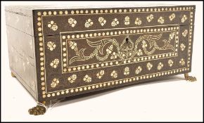 An 18th century Portuguese ebony and ivory inlaid work box raised on brass hairy paw feet with